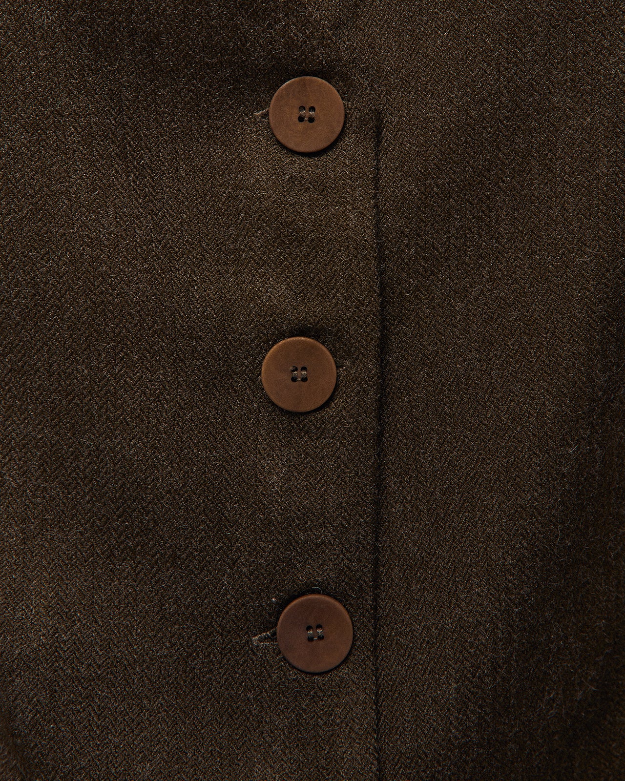 Chaleco verde oscuro con pinzas delanteras, detalle del tejido